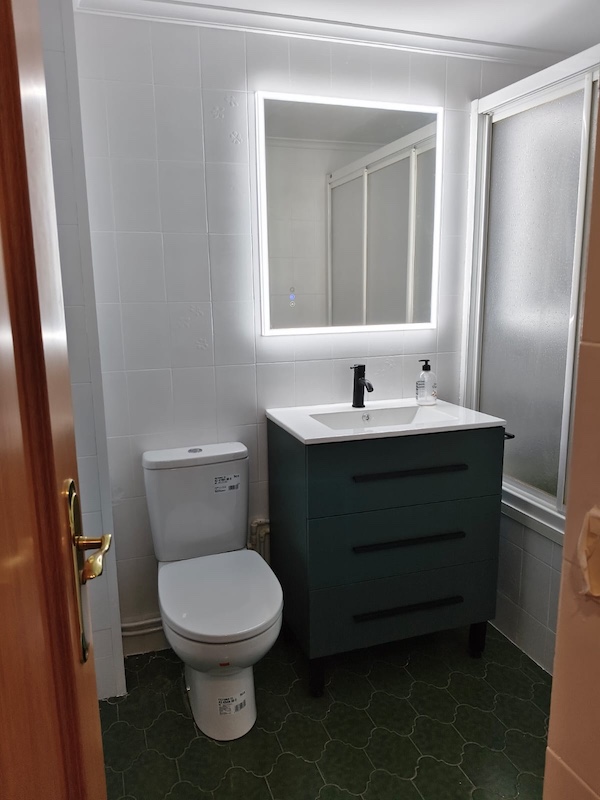 Baño con pared en blanco Wevet y mueble oscuro